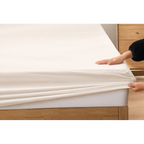 Woman bedding silky-soft white ivory fitted eucalyptus sheets with breathable and hypoallergenic comfort.